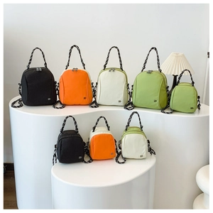 Detail view of colorful nylon shell bags in two sizes with woven handles and metal logos