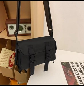 Detail of a black nylon messenger bag with buckle closure and adjustable strap