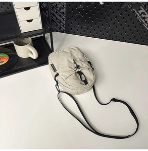 Vue détaillée d'un sac bandoulière en nylon beige avec sangle réglable et design à cordon