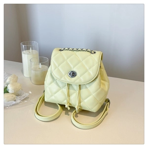 Close-up of quilted pale yellow backpack with silver chain handle and turn-lock closure