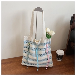 Close-up of knit tote bag featuring blue stripes, openwork texture, and colorful tassels