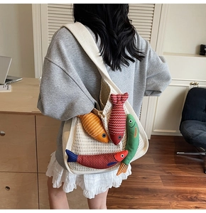 Detailed view of a white crochet tote bag featuring colorful fish-shaped plush ornaments