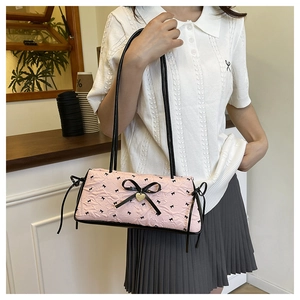 Close-up of pink bow crossbody bag with textured fabric and heart pendant detail