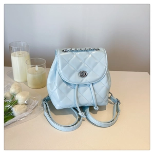 Detail of light blue quilted mini backpack featuring silver chain and turn-lock closure