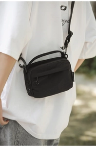 Detailed side view of black crossbody bag showing fabric texture and adjustable strap