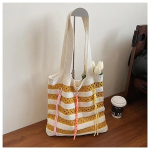 Detail of yellow and white striped knit tote bag with decorative spiral charms and crochet texture
