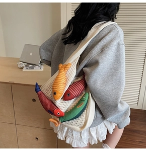 Detail of white mesh tote bag featuring four colorful plush fish charms for a creative look
