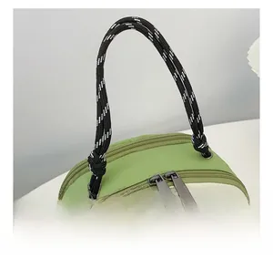 Detail of woven rope handle and dual metal zippers on a green and beige nylon backpack
