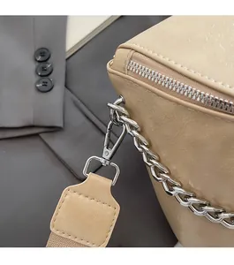 Detailed close-up of glossy leather texture and silver chain hardware on the crossbody bag