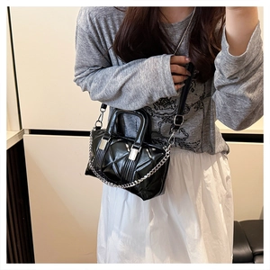 Side view of a quilted black patent leather handbag with silver chain and shoulder strap