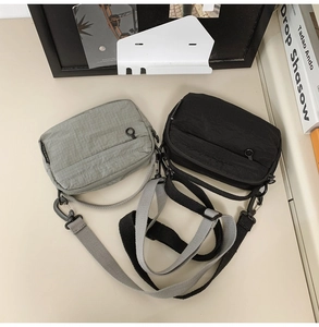 Detail of waterproof nylon crossbody bags in grey and black with zipper pockets