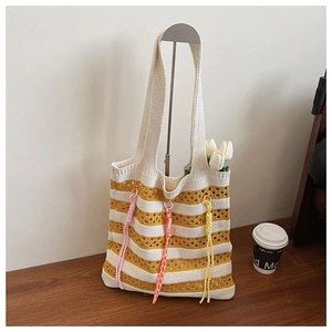 Macro detail of yellow and white striped knit tote bag with colorful decorative tassels