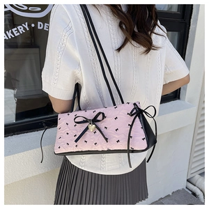 Detail of pink quilted shoulder bag with black bow tie and gold heart pendant