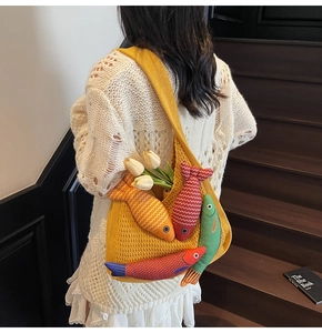 Detail of yellow knit tote bag featuring colorful 3D fish dolls and soft texture