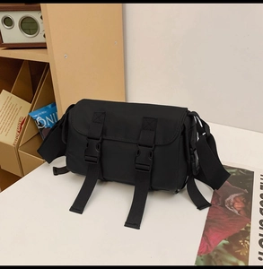 Detail of black tactical messenger bag featuring dual buckle straps and nylon texture
