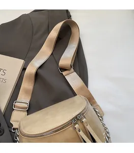 Detail of beige leather crossbody bag with adjustable wide strap and metal chain