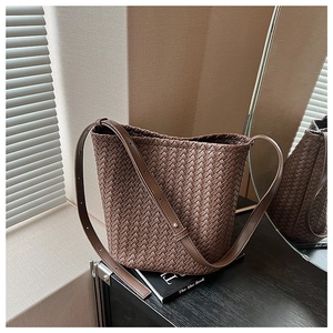 Detail of dark brown woven bucket bag with fine texture on elegant book base