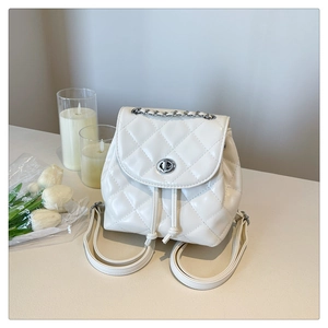 Detail of white quilted backpack with silver chain handle and metallic twist lock