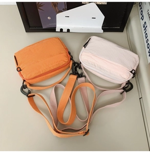 Detail view of two nylon crossbody bags in orange and beige with fine checkered texture