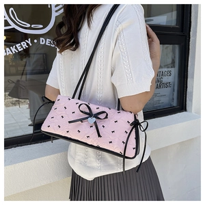 Detailed shot of pink quilted baguette bag with black bows and silver heart charm