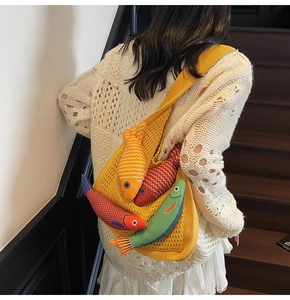 Detail of a yellow knit tote bag featuring three colorful 3D fish charms on a shoulder strap