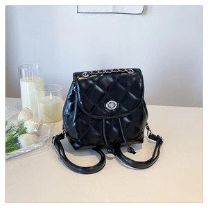 Detail of black quilted mini backpack featuring silver chain handle and turn-lock closure