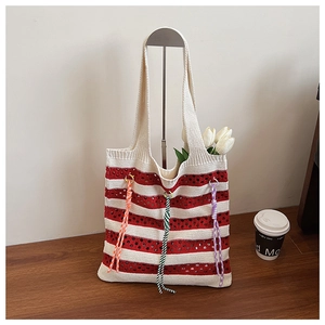 Detail of red and white striped knit tote bag with colorful tassels on a metal stand