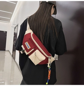 Détail du sac de poitrine bicolore en nylon avec bandoulière et pendentif décoratif
