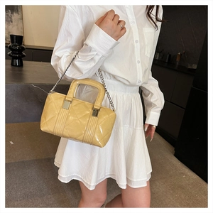 Detail of yellow patent leather quilted pillow bag with silver chain and glossy finish