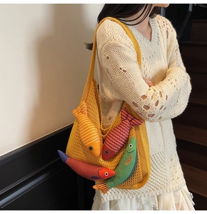 Detail of yellow knit tote bag featuring playful colorful fish charms and wavy texture