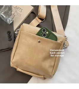Close-up of the back pocket on a beige pebble leather crossbody bag holding a smartphone