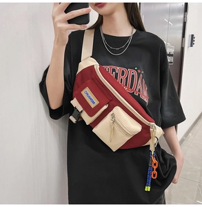 Détail du sac de poitrine bicolore rouge et beige avec chaînes décoratives et poches de rangement
