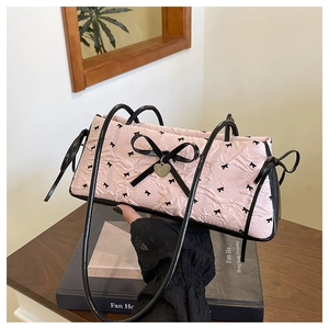 Detail of pink pleated handbag featuring black bow embroidery and heart-shaped pendant