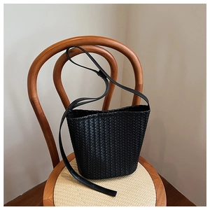 Close-up of black woven leather bucket bag detailing on a vintage wooden chair