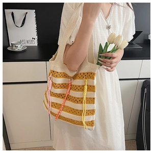 Close-up of yellow and white striped knit tote bag with vibrant colored tassels