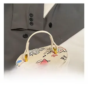 Detailed view of white bucket bag with artistic graffiti prints and gold double zippers