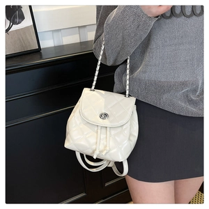 Detailed view of white quilted mini backpack featuring silver clasp and chain strap