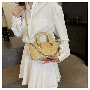 Pale yellow quilted leather handbag with silver chain detail shown on a model