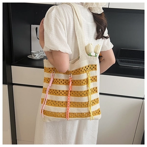 Macro detail of knit tote bag showing yellow stripes and colorful tassel accents