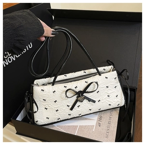 Detailed shot of a quilted white handbag with black bow patterns in a luxury gift box