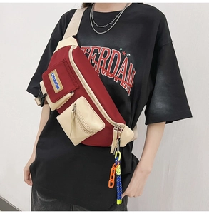 Détail du sac bandoulière bordeaux et beige avec plusieurs poches et pendentif