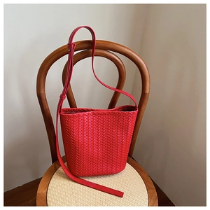 Macro view of a red woven leather bucket bag featuring a detailed Intrecciato pattern