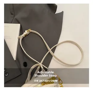 Detailed view of white leather bag with adjustable gold buckle strap on a grey suit