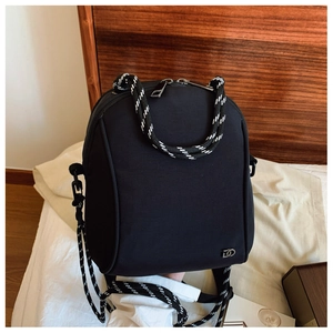 Detail of black nylon shoulder bag featuring stylish black and white woven rope handles
