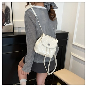 Detail of white quilted leather mini backpack with chain strap and metal turn-lock