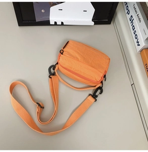 Macro detail of the bright orange nylon bag showing the grid texture and adjustable strap