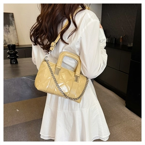 Model view of cream quilted rhombic pillow bag with silver chain and glossy patent finish