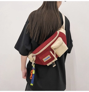 Détail du sac de poitrine bicolore rouge et beige avec fermetures éclair et pendentif