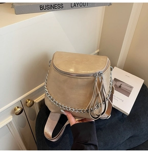 Detail of beige saddle bag with silver chain, wide strap and smooth PU leather texture