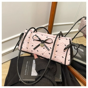 Macro detail of pink quilted bag with black ribbon bows and heart metal pendant charm